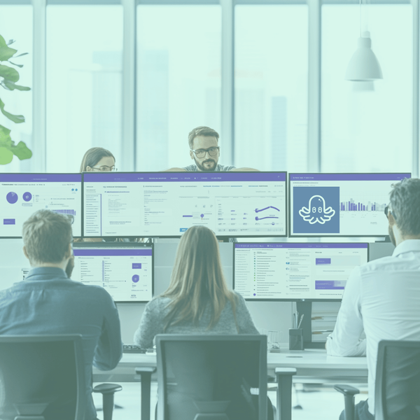 Professional team collaborating in an office setting with multiple computer screens displaying dashboards and automation tools, illustrating productivity and efficiency.